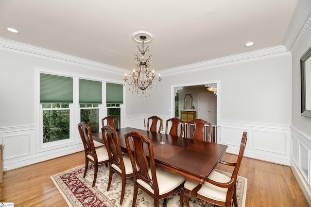 dining area featuring ornamental molding, an inviting chandelier, and light wood-type flooring