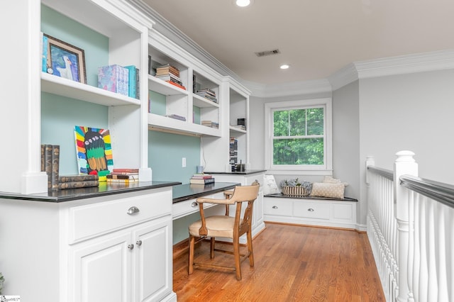 office area featuring crown molding, built in desk, and light hardwood / wood-style flooring