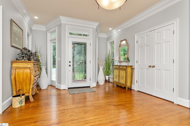 entryway featuring a wealth of natural light, ornamental molding, and light wood-type flooring