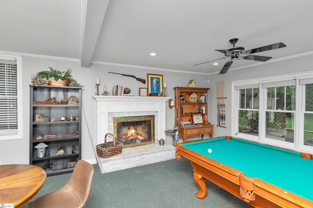 game room with a fireplace, beamed ceiling, ornamental molding, carpet, and ceiling fan