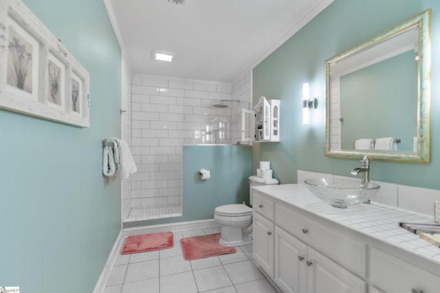 bathroom featuring toilet, a tile shower, ornamental molding, vanity, and tile patterned flooring