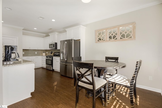 kitchen with dark hardwood / wood-style flooring, decorative backsplash, white cabinets, and appliances with stainless steel finishes