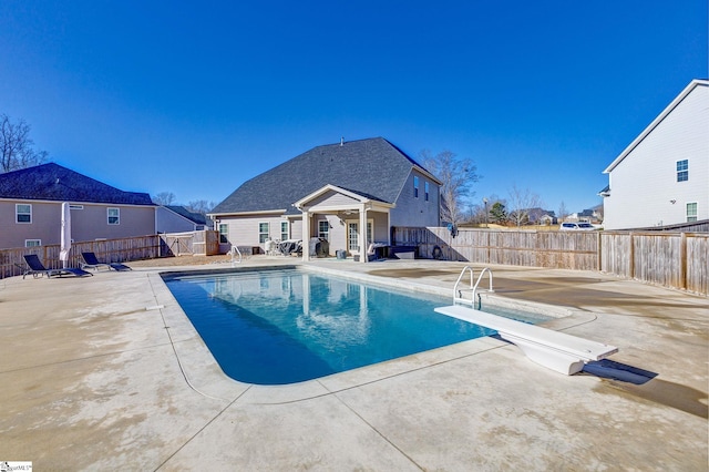 view of pool featuring a diving board and a patio