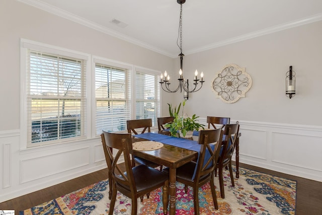 dining room featuring dark wood-type flooring, crown molding, and an inviting chandelier