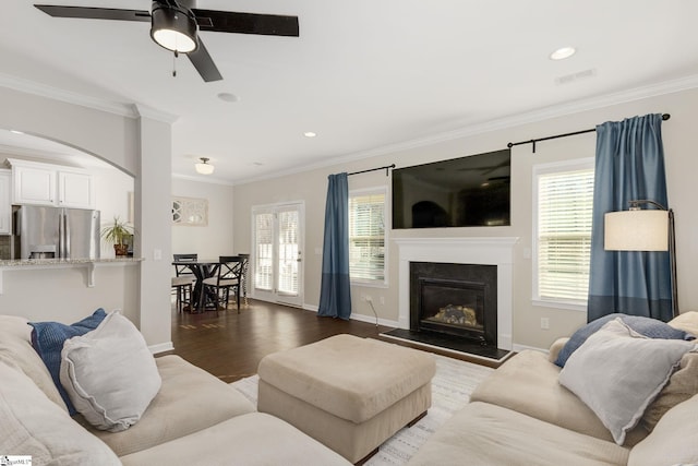 living room featuring ornamental molding, hardwood / wood-style floors, ceiling fan, and a fireplace