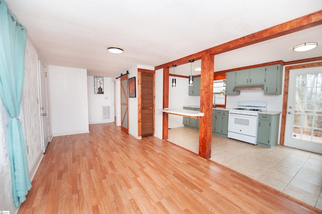 kitchen with white gas range, light hardwood / wood-style flooring, and a barn door