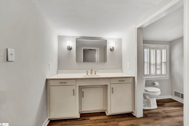 bathroom with vanity, toilet, and hardwood / wood-style floors