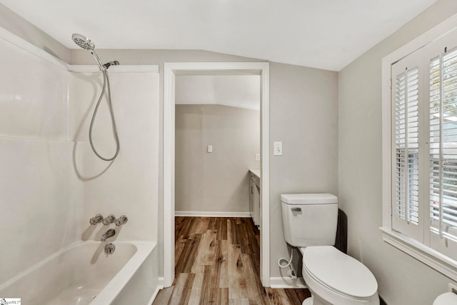 full bathroom with lofted ceiling, hardwood / wood-style floors, vanity, shower / washtub combination, and toilet