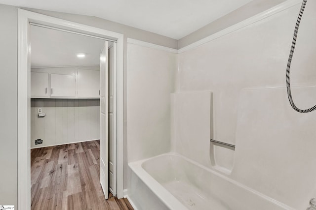 bathroom featuring hardwood / wood-style flooring, a tub, and lofted ceiling