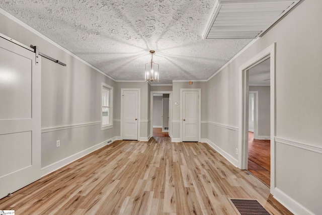 unfurnished bedroom with crown molding, an inviting chandelier, light hardwood / wood-style floors, and a closet