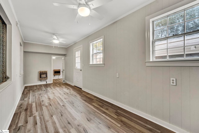 unfurnished living room featuring crown molding, a healthy amount of sunlight, heating unit, and light hardwood / wood-style flooring