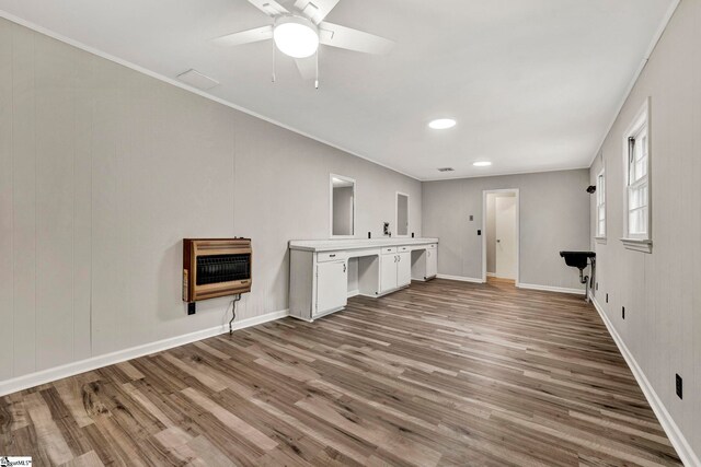 unfurnished living room featuring crown molding, ceiling fan, hardwood / wood-style floors, and heating unit