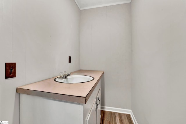 bathroom featuring sink, crown molding, and wood-type flooring