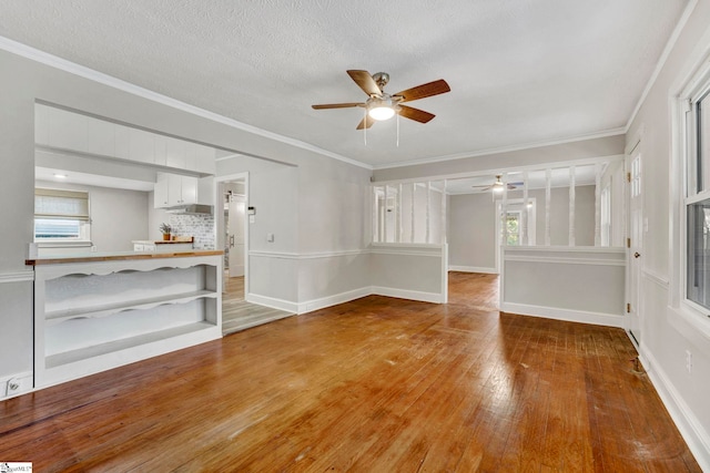 unfurnished living room with hardwood / wood-style flooring, ceiling fan, crown molding, and a textured ceiling