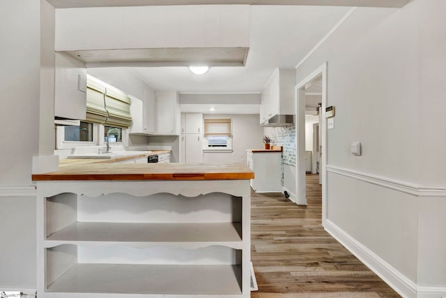 kitchen with light hardwood / wood-style flooring, backsplash, white cabinets, wood counters, and kitchen peninsula