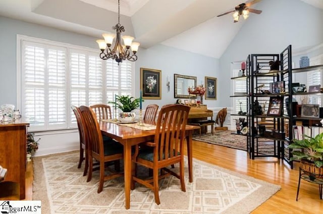 dining space featuring lofted ceiling, ceiling fan with notable chandelier, and light hardwood / wood-style flooring