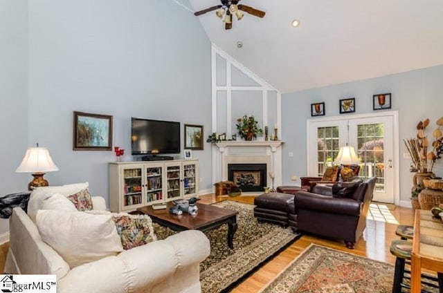 living room with ceiling fan, high vaulted ceiling, and light hardwood / wood-style flooring