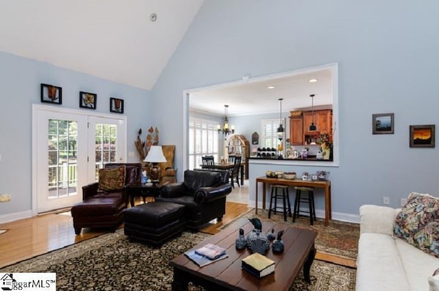 living room with a notable chandelier, high vaulted ceiling, and hardwood / wood-style floors