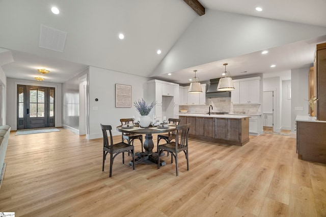 dining room featuring sink, high vaulted ceiling, beamed ceiling, and light wood-type flooring