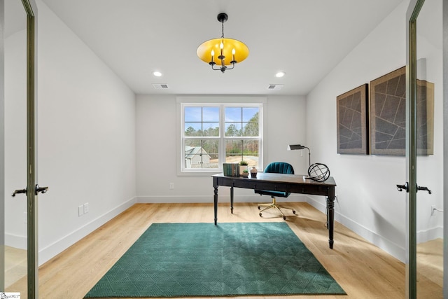 office with hardwood / wood-style floors and a notable chandelier