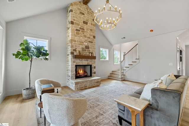 living room with beam ceiling, a stone fireplace, light hardwood / wood-style flooring, and high vaulted ceiling