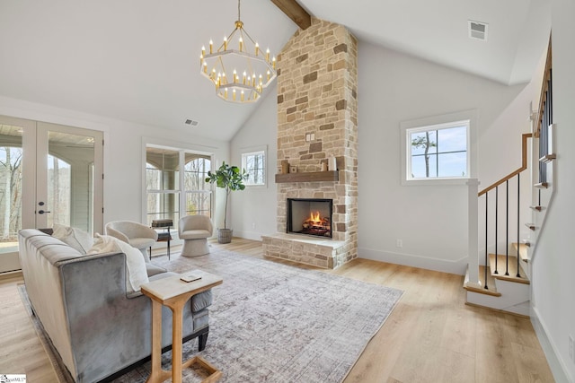 living room featuring high vaulted ceiling, a fireplace, beamed ceiling, light hardwood / wood-style floors, and french doors