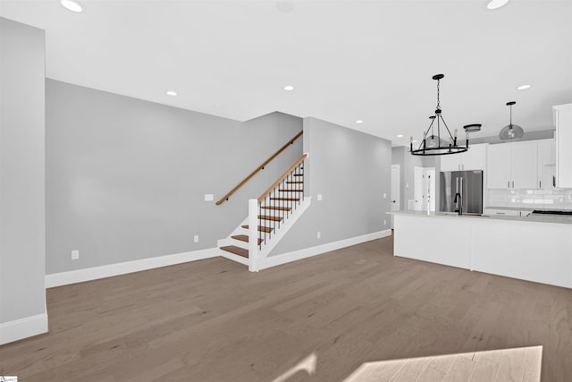 kitchen featuring stainless steel refrigerator, decorative light fixtures, tasteful backsplash, white cabinetry, and light wood-type flooring