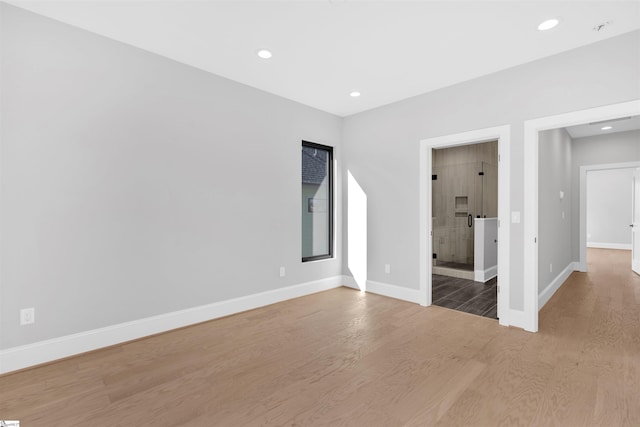 unfurnished bedroom with ensuite bath and hardwood / wood-style flooring