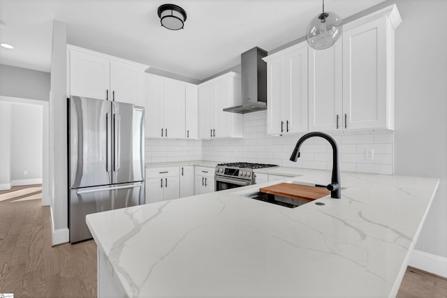 kitchen featuring sink, white cabinetry, light stone counters, stainless steel appliances, and wall chimney range hood