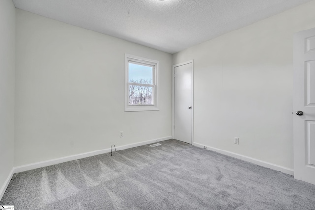 empty room featuring light colored carpet and a textured ceiling