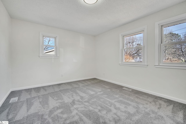 carpeted empty room featuring a textured ceiling