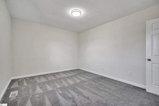 carpeted empty room featuring a textured ceiling