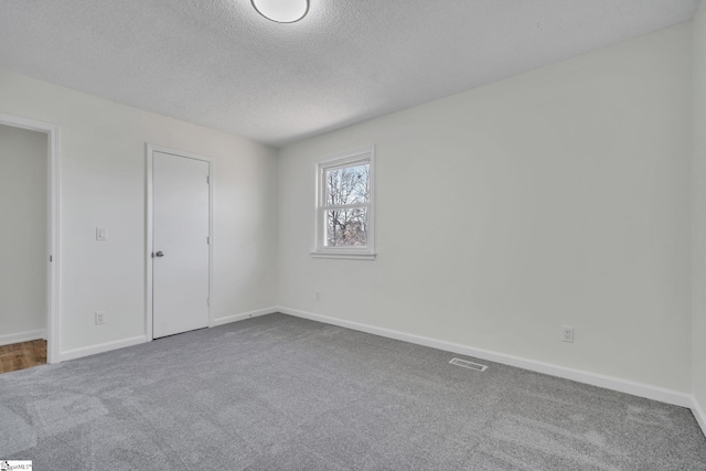 carpeted empty room with a textured ceiling