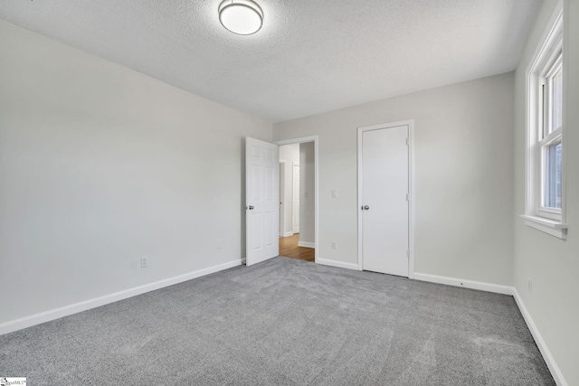 unfurnished bedroom featuring carpet floors, a textured ceiling, and a closet