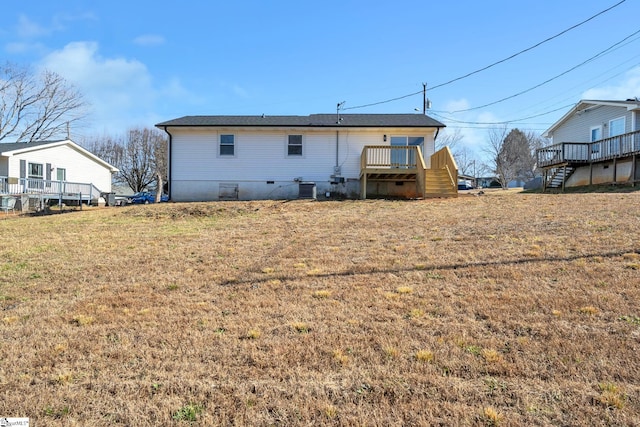 back of house with a deck and a lawn