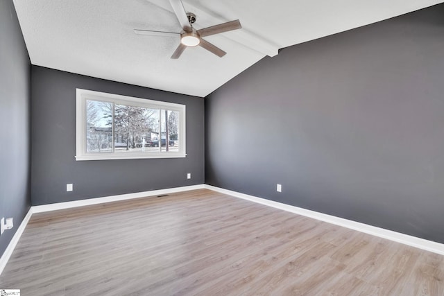 spare room with lofted ceiling with beams, ceiling fan, and light wood-type flooring