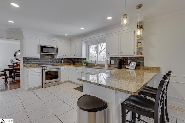 kitchen with stainless steel appliances, kitchen peninsula, and white cabinets