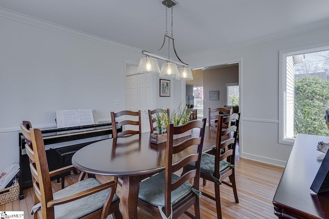 dining space with ornamental molding and light wood-type flooring