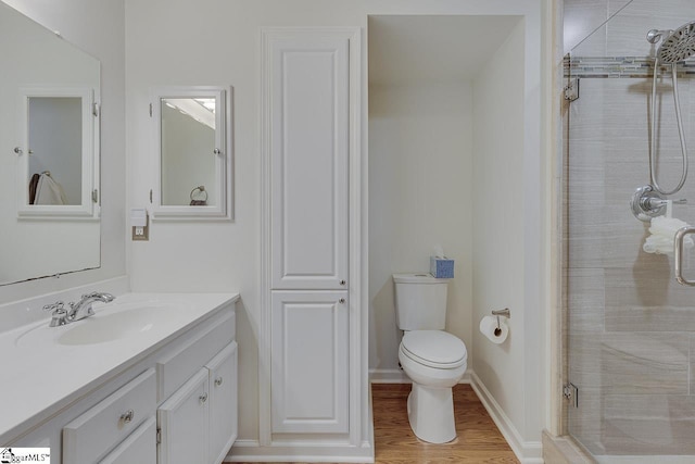 bathroom with vanity, hardwood / wood-style flooring, a shower with shower door, and toilet