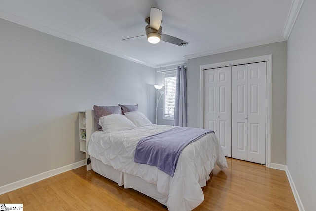 bedroom with crown molding, light wood-type flooring, ceiling fan, and a closet