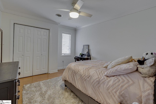 bedroom with crown molding, light hardwood / wood-style flooring, ceiling fan, and a closet