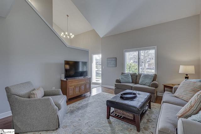 living room with hardwood / wood-style flooring, high vaulted ceiling, and an inviting chandelier