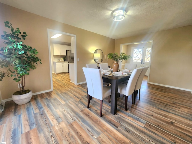 dining room featuring a textured ceiling and light hardwood / wood-style flooring