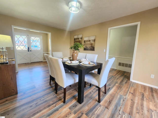 dining room with french doors, hardwood / wood-style floors, and a textured ceiling