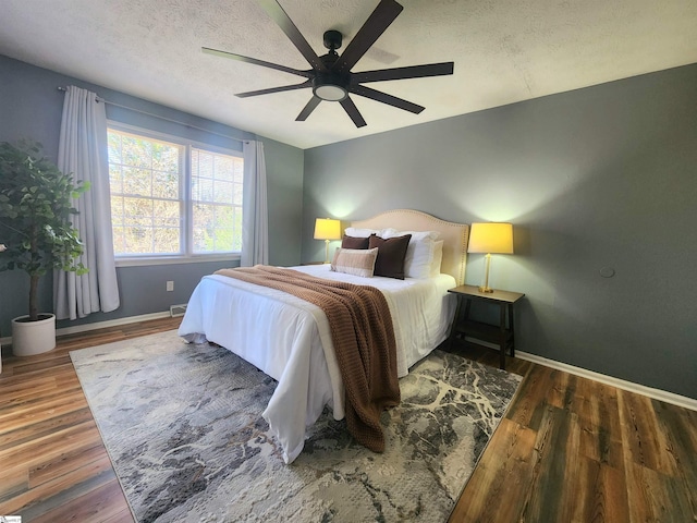 bedroom with ceiling fan, dark hardwood / wood-style flooring, and a textured ceiling