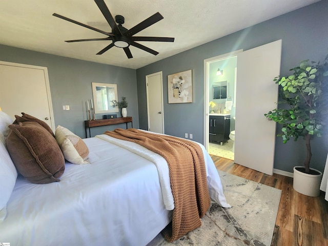 bedroom with connected bathroom, hardwood / wood-style flooring, and ceiling fan