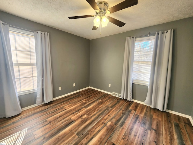 empty room with ceiling fan, dark hardwood / wood-style floors, and a textured ceiling