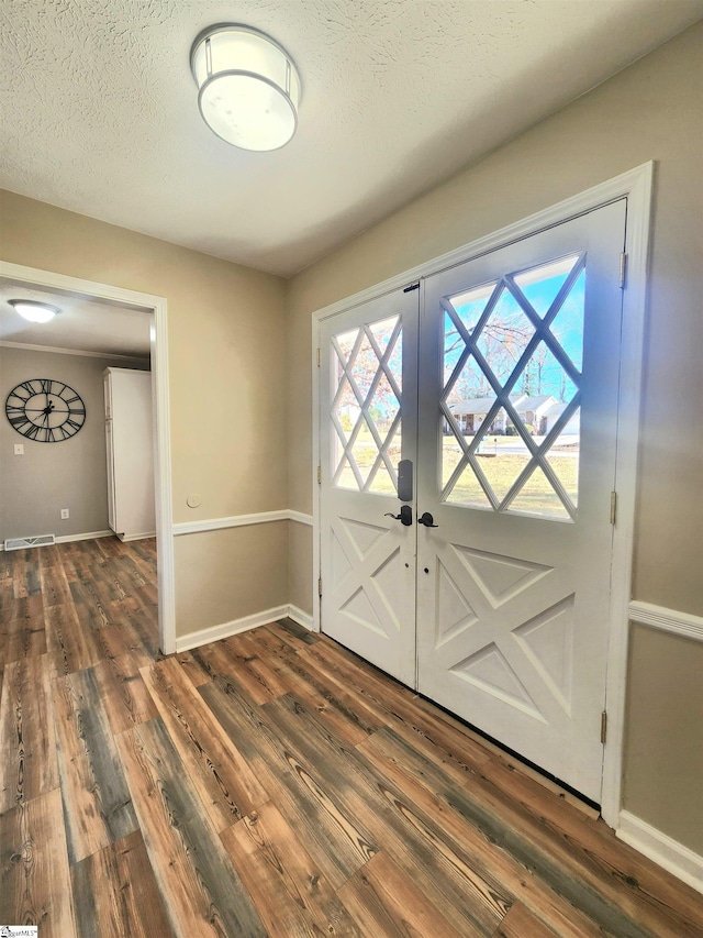 foyer entrance with dark hardwood / wood-style floors, a textured ceiling, and french doors