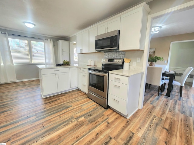 kitchen featuring white cabinetry, kitchen peninsula, light wood-type flooring, and electric stove