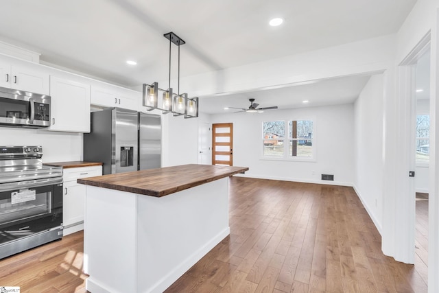 kitchen with white cabinetry, wooden counters, decorative light fixtures, a center island, and appliances with stainless steel finishes